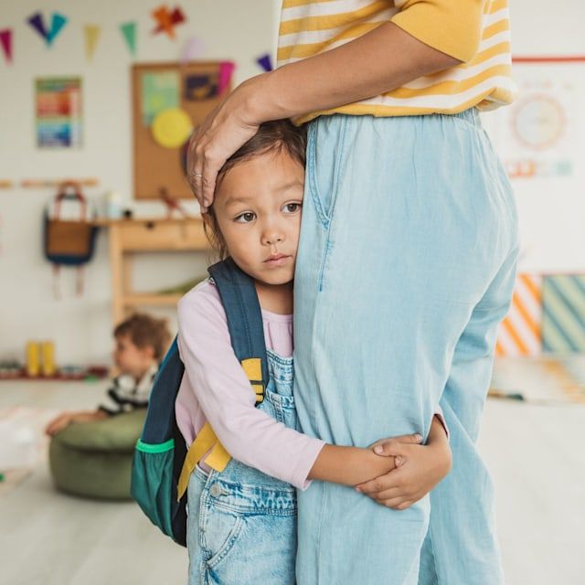 Child clinging to parent's leg with separation anxiety at school