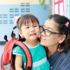 Toddler crying with separation anxiety while mother comforts her at school